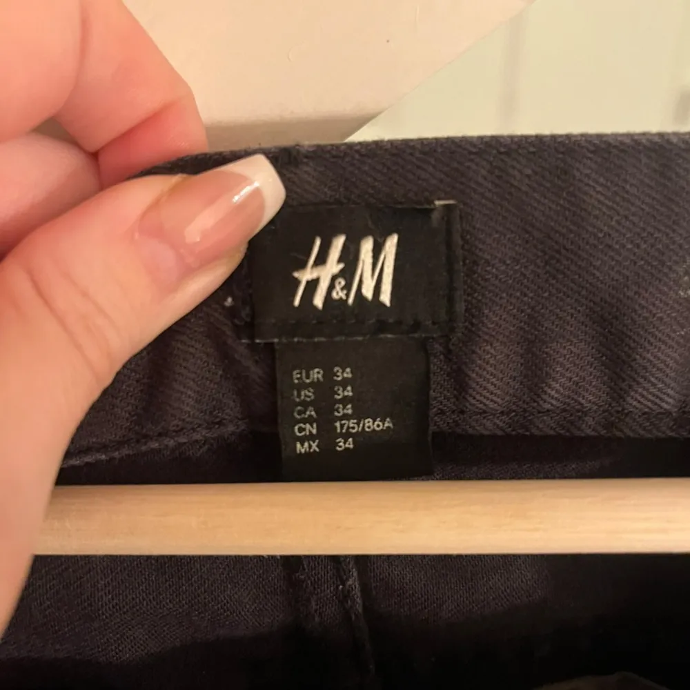 Säljer ett par svarta byxor från H&M i storlek 34. Byxorna har en klassisk design med knapp och dragkedja framtill. De är tillverkade i ett slitstarkt material och har en normal passform. Perfekta för både vardag och fest!. Jeans & Byxor.