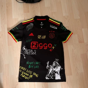 Svart fotbollströja med Bob Marley-motiv - Säljer en svart fotbollströja Ajax x Bob Marley tröja. ny skick aldrig använd. kom privat om ni har frågor🙌👍