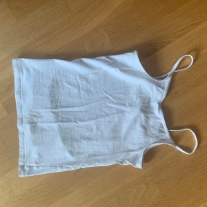 Vitt linne - Vitt linne med smala axelband. Står att det är storlek 146/152 men är som XXS.