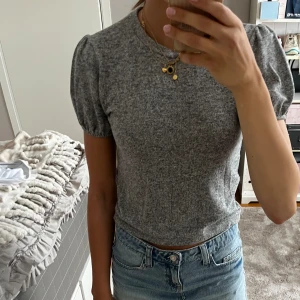 Grå kortärmad topp - Säljer denna söta gråa volangtoppen från zara. Köptes för några år sen och finns inte att köpa längre. Väldigt mjukt och skönt matetial