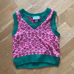 Julig väst av stickat matreal  - Stickad väst med julmotiv och gröna kanter 