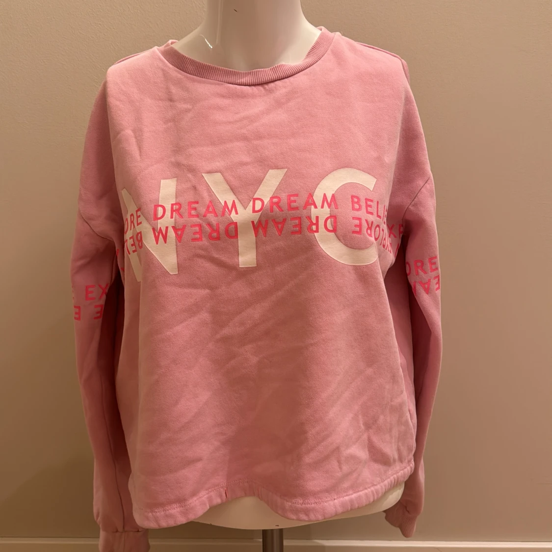 En ljus rosa sweatshirt med rosa och vit text på