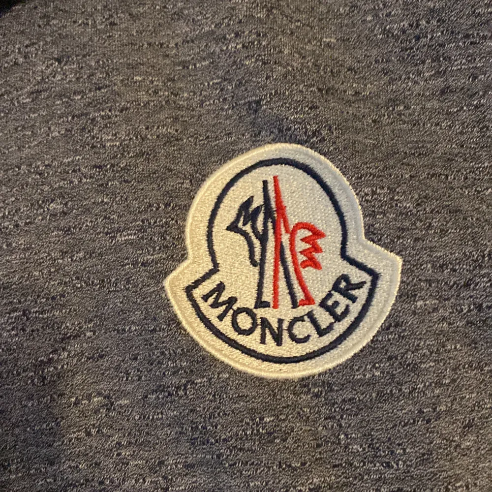 Säljer en snygg grå hoodie från Moncler. Den är i bra skick men dragkedjan är lite sönder så man får dra upp kedjan snabbt. Hoodien har en broderad Moncler-logga på bröstet och är perfekt för höst och vinter. Den är supermjuk och bekväm, perfekt för både vardag och chill.. Tröjor & Koftor.