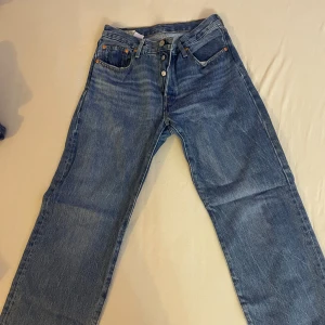 Levi's 501 jeans i blå denim - Säljer ett par klassiska Levi's 501 jeans i blå denim. De är i storlek W26 L30 och har en knappgylf. Jeansen är i bra skick och har den ikoniska Levi's-lappen på baksidan. Perfekta för en avslappnad och stilren look!