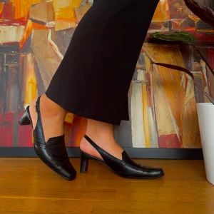 Svarta klackskor från Lloyd - Säljer ett par eleganta svarta klackskor med spetsig tå. Skorna har en bekväm blockklack och en stilren design med en rem runt hälen. Perfekta för både vardag och fest!