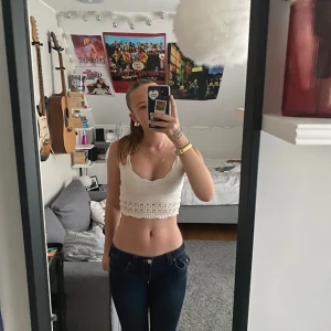 Vit virkad croppad topp - Säljer en superfin vit virkad croppad topp. Den är ärmlös med smala axelband och har en söt spetsdetalj längs nederkanten. Perfekt för sommaren och kan stylas med både jeans och kjol. Toppen är i nyskick och passar perfekt för fest eller en dag på stan.