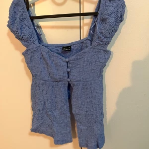 Topp - Blå topp från Nelly i storlek XS. Är i nyskick och använd bara 1 gång tidigare. Nypris är 249kr
