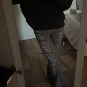 Brun  leopardmönstrade byxor - Snygga grå byxor med leopardmönster. De har en bootcut-stil som ger en trendig look. Perfekta för att sticka ut med ett coolt mönster. Säljer för att dom är för stora så därav aldrig använda eller tvättade! Alltså helt nya! 