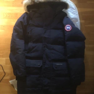 Marinblå dunjacka från Canada Goose emory parka  - Säljer en marinblå dunjacka från Canada Goose med pälsfodrad huva, pälsen på luvan går att ta bort. Perfekt för kalla vinterdagar. Priset kan diskuteras vid snabb affär, hör av er vid frågor eller funderingar. Ny pris 19,3 tusen kr