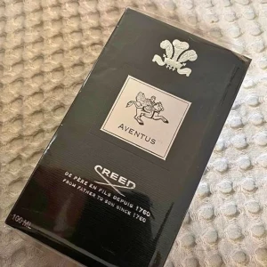 Creed Aventus Parfym 100 ml - Exklusiv Creed Aventus parfym i en elegant glasflaska med svart etikett och silverdetaljer. Förpackningen är stilren och svart med Creed-logotypen och en ryttare i silver. Flaskan rymmer 100 ml av denna ikoniska doft.