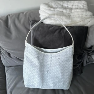 Vit axelväska med mönster - Snygg vit axelväska med ett subtilt mönster och matchande innerficka. Väskan har en enkel axelrem och är perfekt för att bära dina dagliga nödvändigheter. Den stilrena designen gör den lätt att matcha med olika outfits.
