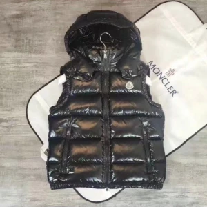 Svart dunväst från Moncler - Snygg svart dunväst från Moncler med glansig finish och dragkedja framtill. Västen har en praktisk huva och flera fickor med dragkedja. Perfekt för kyligare dagar när du vill hålla stilen. Storlek: S, M, L, XL och 2XL