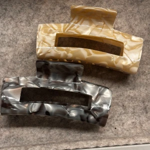 Hårklämmor i marmorlook - Två stiliga hårklämmor i marmorlook, en i beige och en i grått. Perfekta för att hålla håret på plats med stil. Klämmorna har en rektangulär form och är tillverkade i ett glansigt material. En har gått sönder men är laggad med super starkt lim, och är som ny, de syns inte heller!
