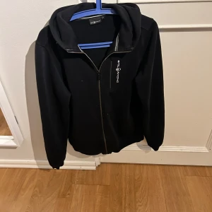 Svart hoodie från Sail Racing - Snygg svart hoodie från Sail Racing med dragkedja och logga på bröstet. Perfekt för en avslappnad stil. För liten för mig och säljer därför. Vid snabb affär kan priset ändras. 9,5/10 skick!