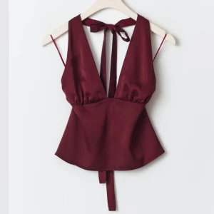 Vinröd halterneck topp - Helt oanvänd, prislappen kvar! Nypris 360kr. Snygg vinröd halterneck topp med djup urringning och knytband i nacken och ryggen. 