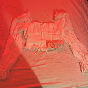 Vit blus med volangdetaljer - Charmig vit blus med volangdetaljer och knytning framtill. Aldrig använd med prislappen kvar