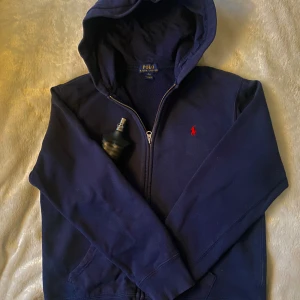 Mörkblå zip hoodie Ralph Lauren - Säljer en snygg mörkblå hoodie från Ralph Lauren med dragkedja och den klassiska röda loggan på bröstet. Mycket bra kondition 9/10. Perfekt nu inför vintern. Skriv om det undras något💯