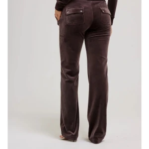 Bruna mjukisbyxor med fickor - Säljer ett par bruna och svarta juicy couture mjukisbyxor med fickor och dragkedja. Byxorna har en loose passform och är perfekta för en avslappnad stil. Finns även i svart och rött(se min profil, strl xs). 