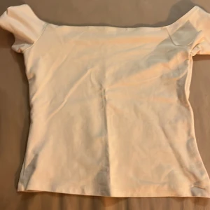 Vit offshoulder topp - Säljer en stilren vit offshoulder topp. Perfekt för sommardagar med sin enkla och eleganta design. Toppen har en tight passform och korta ärmar. Från bik bok. Den är använde endast en gång och storleken vet jag inte, men passar xs-s