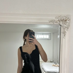 Svart ribbad topp från H&M - Snygg svart ribbad topp från H&M med breda axelband och en elegant v-ringning. Perfekt för en stilren look.