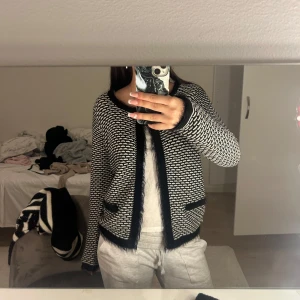 Svartvit mönstrad kofta - Säljer en stilren svartvit kofta med ett unikt mönster. Koftan har långa ärmar och svarta kanter som ger en snygg kontrast. Perfekt för att lägga till en touch av elegans till din outfit.