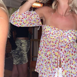 Blommig offshoulder topp - Säljer en färgglad blommig offshoulder topp med knytning framtill. Perfekt för sommarens alla tillfällen. Toppen har långa ärmar och en luftig passform.