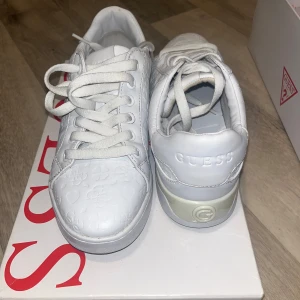 Vita sneakers från Guess - Snygga vita sneakers från Guess med diskret mönster och snörning. Perfekta för en stilren look. Endast använda en gång ( studenten) 