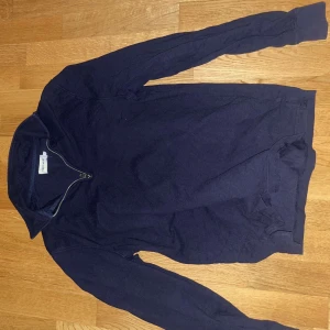 Mörkblå tröja med dragkedja - Säljer en stilren mörkblå tröja med quarter-zip. Perfekt för kyligare dagar och enkel att matcha med andra plagg. Tröjan har långa ärmar och en bekväm passform.
