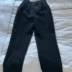 Svarta kostymbyxor från Zara - Snygga svarta kostymbyxor från Zara i storlek XS. Byxorna har en klassisk design med hög midja och raka ben, perfekta för en stilren look. Tillverkade i ett bekvämt material som passar både till vardags och mer formella tillfällen.
