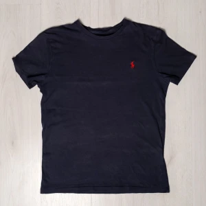 Mörkblå Ralph Lauren T-Shirt  - Säljer en snygg mörkblå t-shirt från Ralph Lauren i bomull. Den har en klassisk passform och är kortärmad med det ikoniska röda broderade logotypen på bröstet. Väldigt fick skick. Storlek M. Pris kan diskuteras! Fri frakt!
