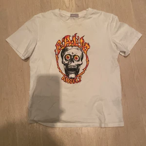 Vit t-shirt med tryck från Palm Angels - Cool vit t-shirt från Palm Angels med ett färgstarkt tryck av en dödskalle omgiven av eldflammor och texten 'Palm Angels'. Perfekt för en edgy look.