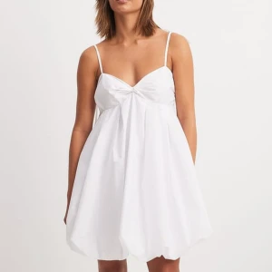 Vit kortklänning med smala axelband - Snygg vit kortklänning med smala axelband och en luftig passform. Enbart testad så lapp är kvar , köpt för att vara en studentklänning 