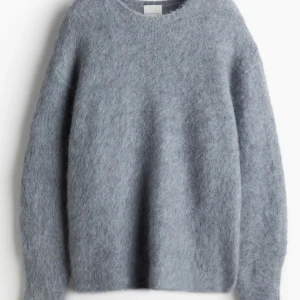 Stickad tröja i Mohairmix, H&M Premium Selection - En tröja i mjuk, lurvig kvalitet med inslag av ull och mohair. Tröjan har lös passform, rund halsringning, nedhasad axel och voluminös, extra lång ärm som smalnar av vid armslut. 