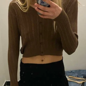 Brun kofta med knappar brandy melville  - Säljer min brandy Melville kofta, brun kofta med knappar och ett fint hålmönster. Koftan är croppad och har långa ärmar, perfekt för lager på lager-stil. Passar bra till både vardag och lite finare tillfällen.