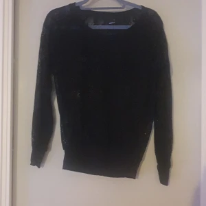 Svart spetsblus från Gina Tricot - Elegant svart spetsblus från Gina Tricot med långärmad design. Perfekt för en stilren look med vackra spetsdetaljer som ger en feminin touch. Passar utmärkt till både vardag och fest.