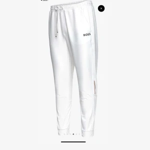 Vita mjukisbyxor från Boss - Snygga vita mjukisbyxor från Boss med elastisk midja och snörning. Byxorna har en stilren design med logotyp på benet och praktiska fickor. Perfekta för en avslappnad stil. Ordpris:1800 