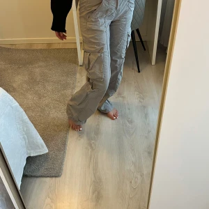 Grå cargobyxor från H&M - Snygga grå cargobyxor från H&M med flera praktiska fickor. Byxorna har en loose passform och är tillverkade i 100% bomull, vilket gör dem bekväma och slitstarka. Perfekta för en avslappnad stil.