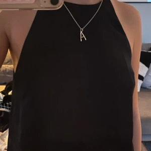 Svart ärmlös topp - Snygg svart ärmlös topp i ett elegant och stilrent snitt. Perfekt för en kväll ute eller en speciell tillställning. Toppen har en enkel design som gör den lätt att matcha med accessoarer.