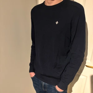 Mörkblå tröja från Morris - Snygg mörkblå tröja från Morris med en liten broderad logga på bröstet. Tröjan har långa ärmar och en klassisk rund halsringning. Perfekt för en stilren look.