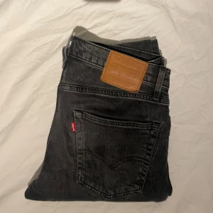 Svarta Levis 502 jeans - Tjena, säljer ett par snygga svarta Levis 502 jeans med klassisk femficksdesign och knappgylf. De har en normal passform och är tillverkade i slitstarkt denim. Perfekta för en stilren look. W30 L32, hör av dig om du har frågor😁