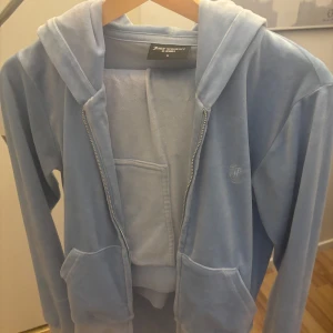 Ljusblå hoodie från Juicy Couture - Säljer en supermjuk ljusblå hoodie från Juicy Couture och byxorna. Tröjan har lite tecken på användning men inget man märker av. 