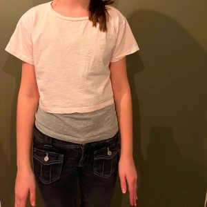 Ljusrosa croppad t-shirt - Säljer en enkel och stilren vit croppad t-shirt med korta ärmar. Perfekt för en avslappnad look. Passar bra till jeans eller kjol.