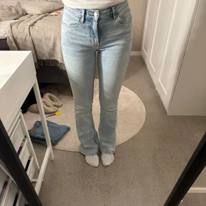Ljusblå bootcut jeans - Snygga ljusblå bootcut jeans med låg midja, hamnar lite under naveln på mig. Perfekta för olika stilar. Passar bra till både sneakers och klackar. Jeansen har en liten fläck ner på ena benet men inget man tänker på. Skriv för fler bilder. 