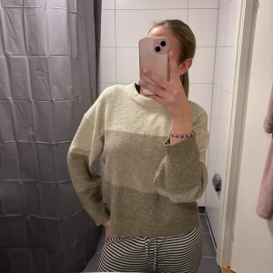 Beige och grå stickad tröja - Mysig stickad tröja i beige och grått med långa ärmar. Perfekt för kyligare dagar och ger en avslappnad stil. Passar bra till både jeans och kjol.