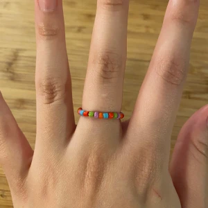 Flerfärgad ring, pärlor - Egentillverkad ring av pärlor och ståltråd💜ca 6cm omkrets och ca 16mm diameter. Går att beställa i valfri färg/färger💅🏼