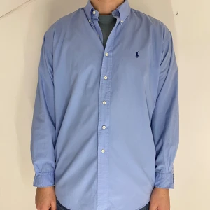 Blå skjorta från Ralph Lauren - Snygg blå skjorta från Ralph Lauren i 100% bomull. Modell blake. Storlek large. Modellen är 193cm lång och väger 85kg. 