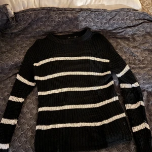 Svart och vit randig stickad tröja - Säljer en svart stickad tröja med vita ränder. Tröjan har långa ärmar och en bekväm passform. Tröjan är från Lager 157 i Storlek S. 