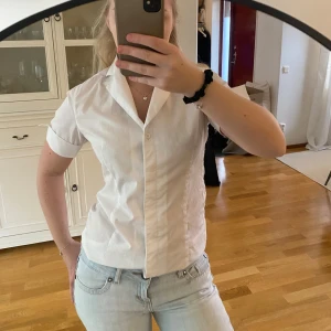 Vit kortärmad skjorta - Säljer en stilren vit kortärmad skjorta med knappar framtill. 