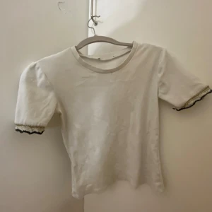 Vit kortärmad topp med spetsdetaljer - Vit tröja med spets på ärmarna från Zara!! En liten fläck som inte försvinner därav priset. Hör av er vid frågor!!