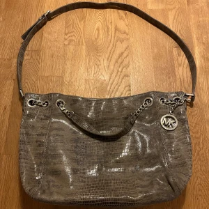 Michael Kors - Michael Kors väska i skin med beigegrå färg. Knappa använd. Kan användas med långt eller kort band. Många innerfickor 